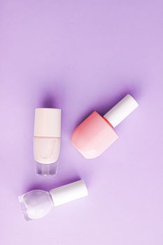 Nail polish bottles on purple background, beauty branding