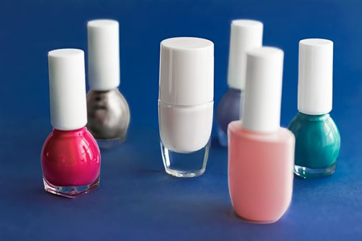 Nail polish bottles on dark blue background, beauty branding