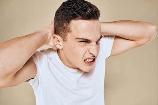 Man with displeased facial expression emotions white t-shirt gestures with hands beige background. High quality photo