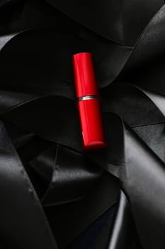 Red lipstick on black silk background, luxury make-up and beauty cosmetics