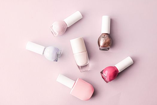 Nail polish bottles on blush pink background, beauty branding