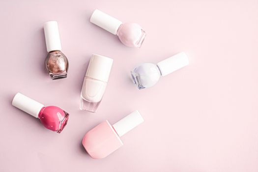 Nail polish bottles on blush pink background, beauty branding