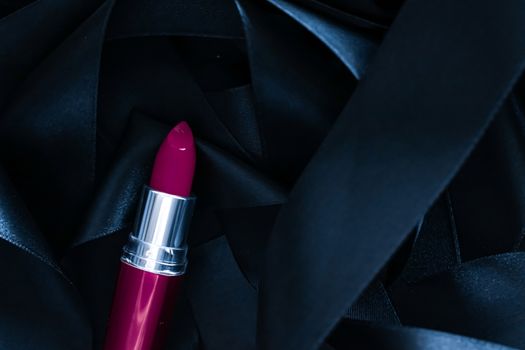 Purple lipstick on black silk background, luxury make-up and beauty cosmetics
