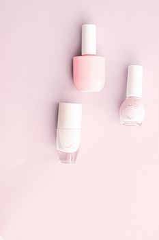 Nail polish bottles on blush pink background, beauty branding