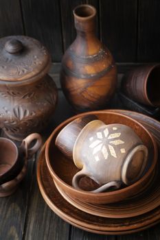 Many empty brown clay bowls and plates on old textured wooden table. Traditional culture about ceramics, pottery, handycraft, handmade kitchenware from natural material