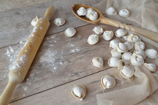 Raw dumplings with rolled for homemade russian pelmeni. On white rustic background