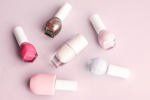 Nail polish bottles on blush pink background, beauty branding