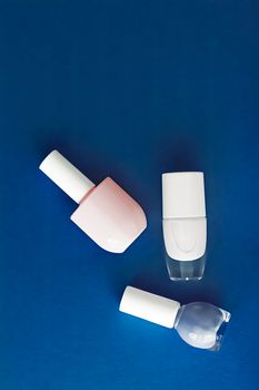 Nail polish bottles on dark blue background, beauty branding