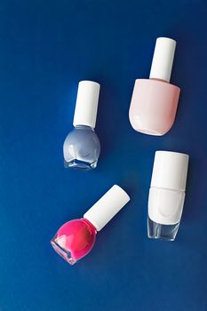 Nail polish bottles on dark blue background, beauty branding