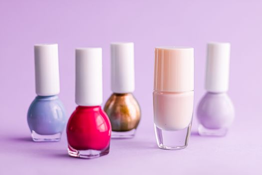 Nail polish bottles on purple background, beauty branding