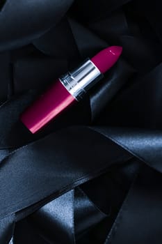 Purple lipstick on black silk background, luxury make-up and beauty cosmetics