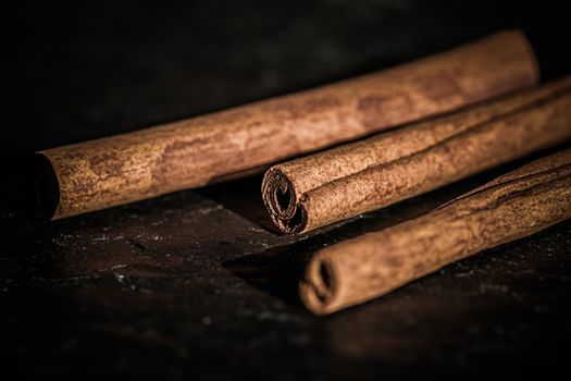 Cinnamon sticks on black stone background, food recipes