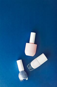 Nail polish bottles on dark blue background, beauty branding