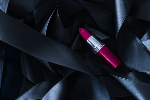 Purple lipstick on black silk background, luxury make-up and beauty cosmetics