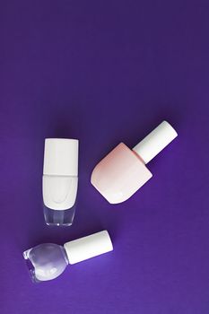 Nail polish bottles on dark purple background, beauty branding