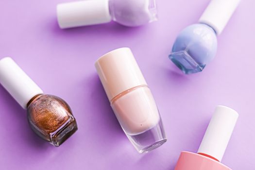 Nail polish bottles on purple background, beauty branding