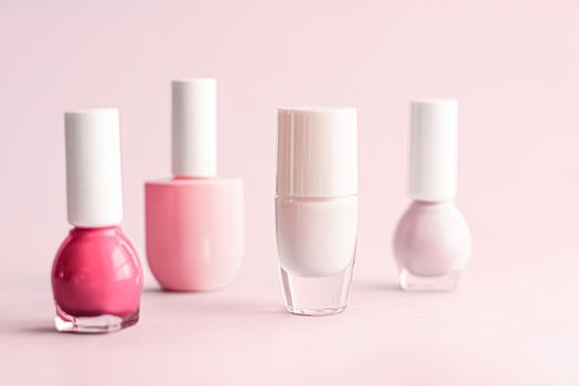 Nail polish bottles on blush pink background, beauty branding