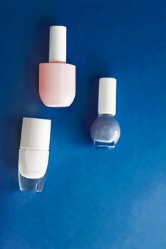 Nail polish bottles on dark blue background, beauty branding