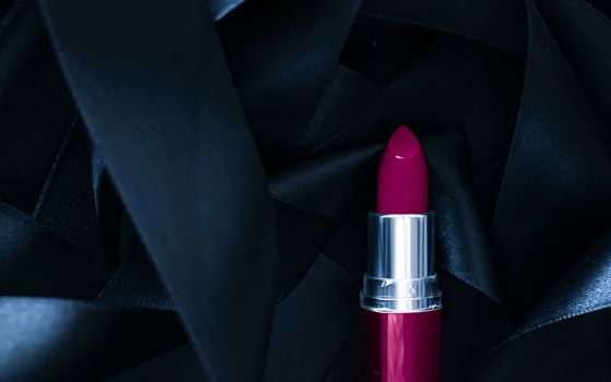 Purple lipstick on black silk background, luxury make-up and beauty cosmetics