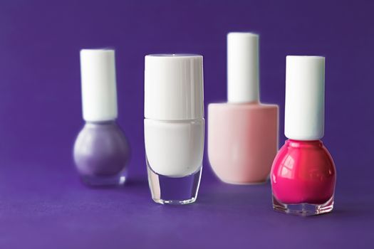 Nail polish bottles on dark purple background, beauty branding