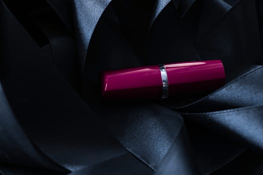 Purple lipstick on black silk background, luxury make-up and beauty cosmetics