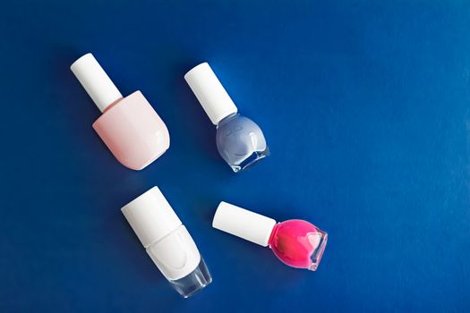 Nail polish bottles on dark blue background, beauty branding