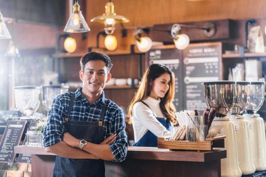Portrait of Asian Young Small business owner with coffee shop in front of counter bar, entrepreneur and startup, preparing for service to customer in cafe store and restaurant,business partner concept