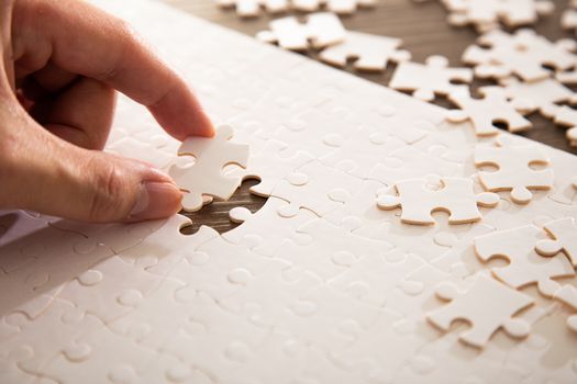 Hand putting the a last piece of white jigsaw puzzle on color background and place for your content
