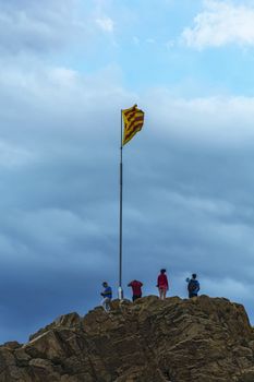 Spain, Blanes - September 14, 2017: Tourists about the State of the flag of Spain on top of the rock Sa Palomera (Spain, Blanes)