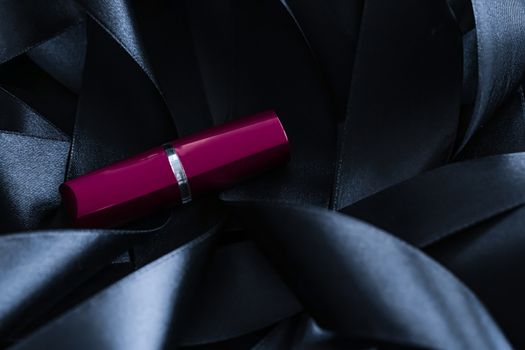 Purple lipstick on black silk background, luxury make-up and beauty cosmetics