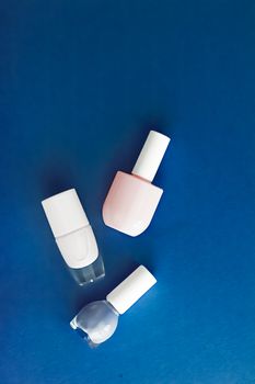 Nail polish bottles on dark blue background, beauty branding