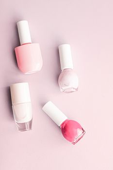 Nail polish bottles on blush pink background, beauty branding