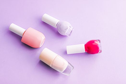 Nail polish bottles on purple background, beauty branding