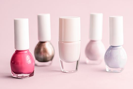 Nail polish bottles on blush pink background, beauty branding