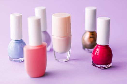 Nail polish bottles on purple background, beauty branding