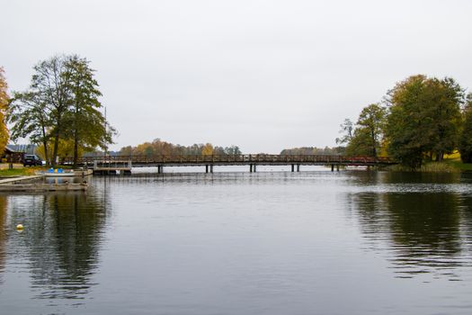 Bridge in Galve lake in Trakai, Lithuania. Autumn trees and cloudy weather.