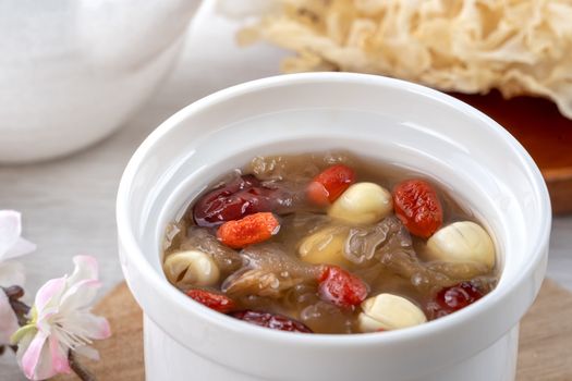 Close up of traditional Chinese sweet snow white fungus soup with lotus seed, red dates (jujube) and wolfberry (goji, gojiberry) on white background.