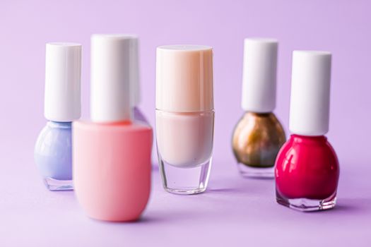 Nail polish bottles on purple background, beauty branding