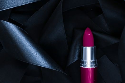 Purple lipstick on black silk background, luxury make-up and beauty cosmetics