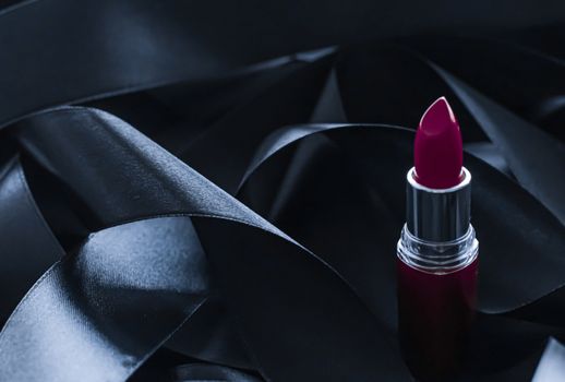 Purple lipstick on black silk background, luxury make-up and beauty cosmetics