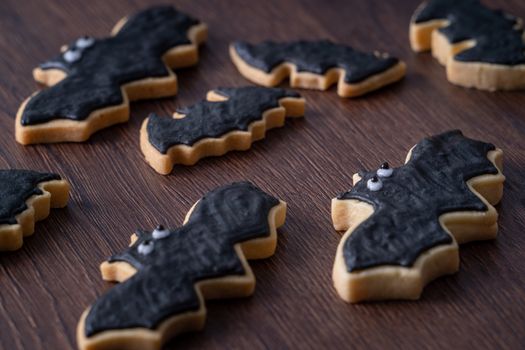 Close up of decorating cute Halloween bat gingerbread sugar cookies with frosting icing cream topping bag.