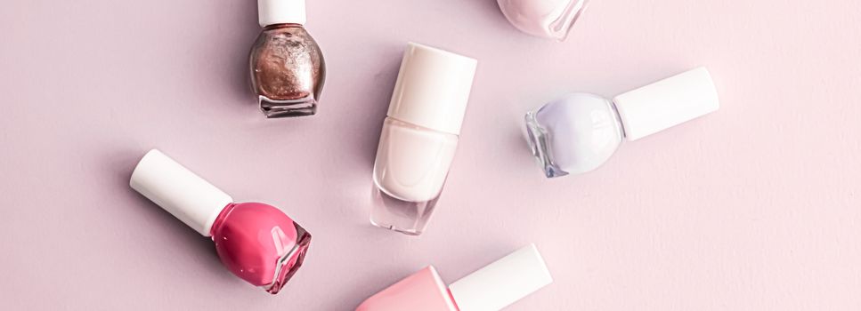 Nail polish bottles on blush pink background, beauty branding