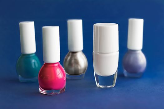 Nail polish bottles on dark blue background, beauty branding