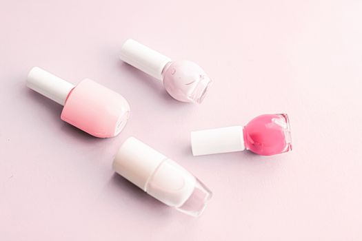 Nail polish bottles on blush pink background, beauty branding