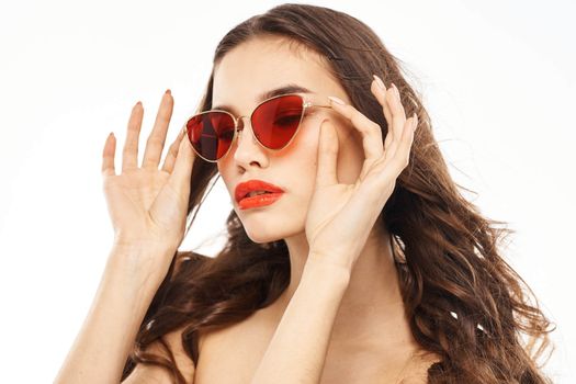 Portrait of brunette woman in sunglasses naked shoulders light background. High quality photo