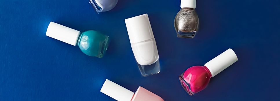 Nail polish bottles on dark blue background, beauty branding