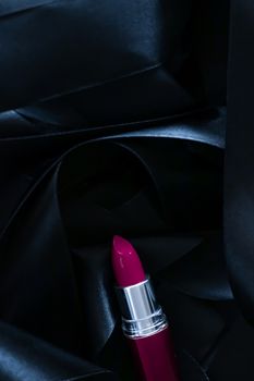 Purple lipstick on black silk background, luxury make-up and beauty cosmetics