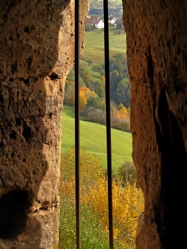 view through a castle loopholes to autumnal colored Germany