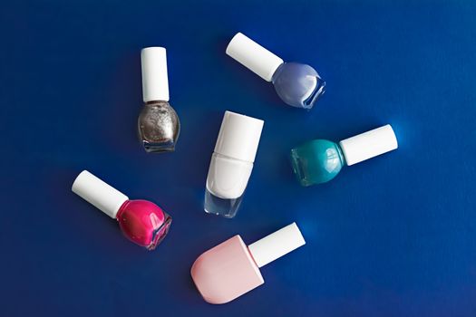 Nail polish bottles on dark blue background, beauty branding