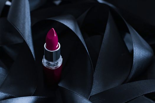 Purple lipstick on black silk background, luxury make-up and beauty cosmetics